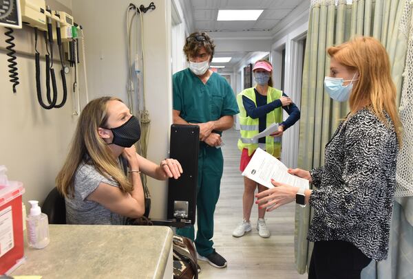 Kjisten Osvold (left) asks questions to Dr. Nick Beaulieu (second from left) and Kelsey Williams (right), a physician assistant student, as Stefanie Agusta (third from left), a volunteer, looks on after Osvold received the Moderna COVID-19 vaccine at Highland Urgent Care & Family Medicine in Atlanta on Thursday. (Hyosub Shin / Hyosub.Shin@ajc.com)