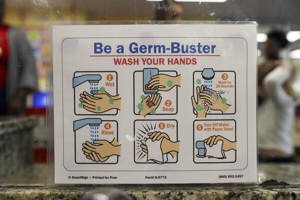 In this file photo, a hand-washing instruction sign is displayed near the sinks for students at the Kids R Kids Learning Academy day care center in Marietta. ALYSSA POINTER / ALYSSA.POINTER@AJC.COM