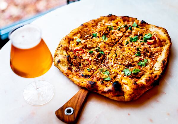 A pizza topped with Thai chile sausage, peanut sauce, pickled peppers and cilantro  with a house-brewed beer. CONTRIBUTED BY HENRI HOLLIS