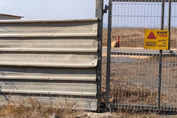 A sign warning of mines hangs on a gate in the tiny settlement of "Trump Heights" in the Israeli-controlled Golan Heights, where Israeli residents are welcoming the election of their namesake. They hope Donald Trump's return to the U.S. presidency will breathe new life into the community. Thursday, Nov. 7, 2024. (AP Photo/Ariel Schalit)