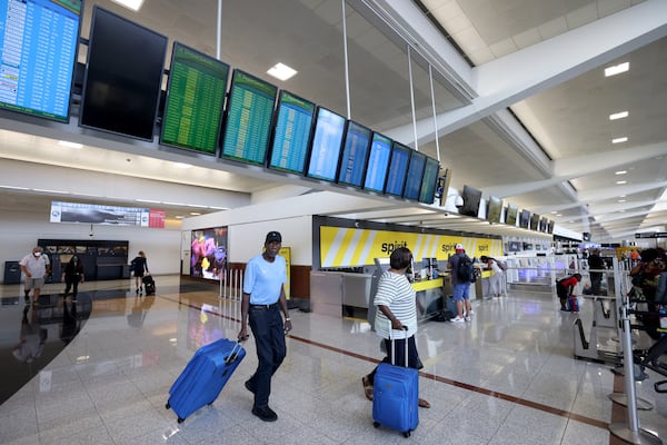 Travelers pass under screens listing departures at the North Terminal check-in at Hartsfield-Jackson. The airport's slate of expansion projects won’t be easy on travelers, and navigating through an airport constantly under construction can be a headache. (Jason Getz / Jason.Getz@ajc.com)