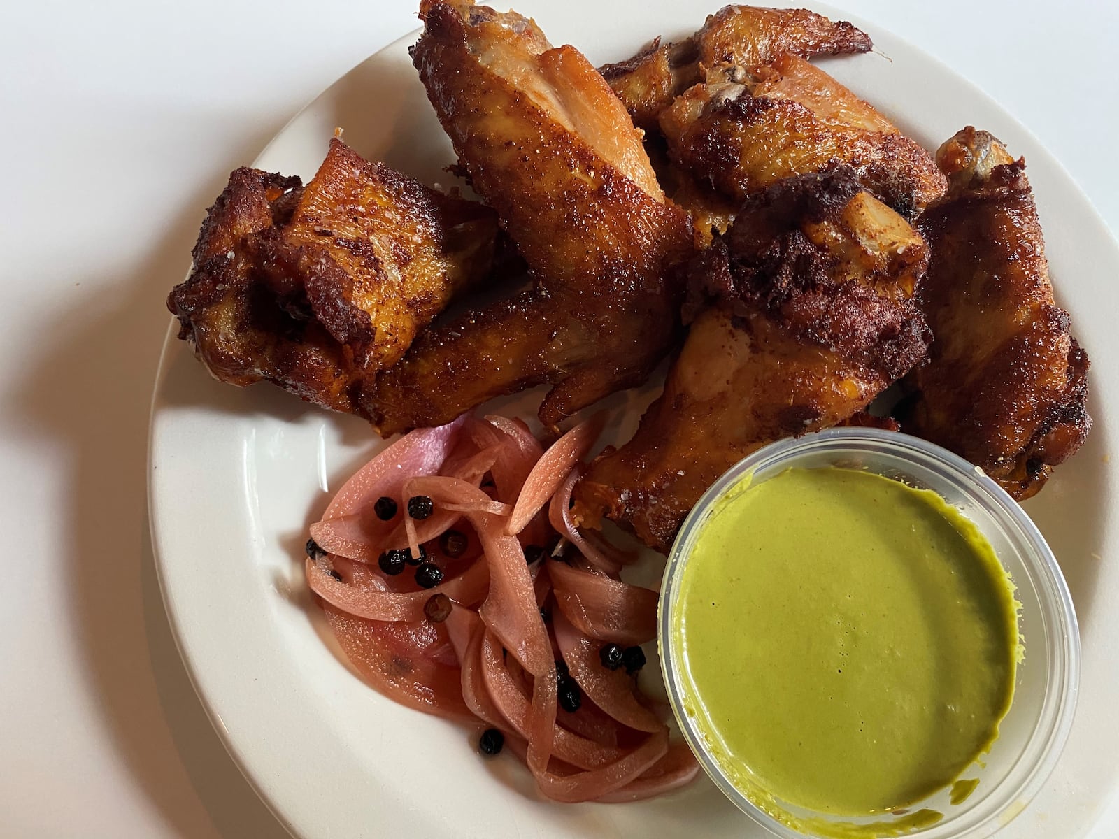 Seven Lamps offers wings that are smoked, then fried, with pickled red onion, cilantro and aji verde. CONTRIBUTED BY BOB TOWNSEND
