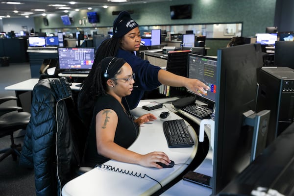 A communications officer trainee gets help from her trainer at DeKalb County's 911 call center at the county police department in February. In December, the county was answering nearly 64% of 911 calls within 20 seconds. (Jason Getz/AJC)