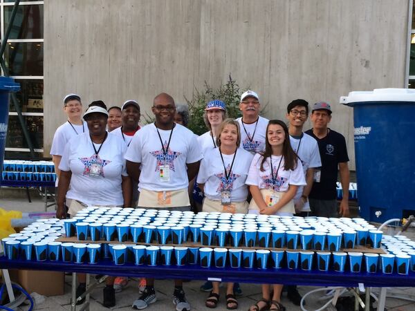 John Prevost, wearing a black T-shirt on the right, stands with other volunteers at a water station in 2017 at The Atlanta Journal-Constitution Peachtree Road Race. (Courtesy of John Prevost)