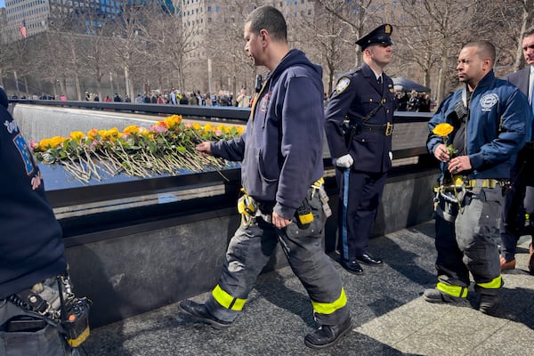 A firefighter places a flower on the names of the deceased during a ceremony marking the anniversary of the 1993 World Trade Center bombing at the 9/11 Memorial, Wednesday, Feb. 26, 2025, in New York. (AP Photo/John Minchillo)