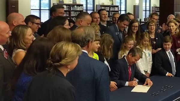 May 2, 2019, Marietta -- Gov. Brian Kemp, flanked by children, parents, lawmakers and educators, signs new dyslexia mandate during ceremony at Wheeler High School Thursday.