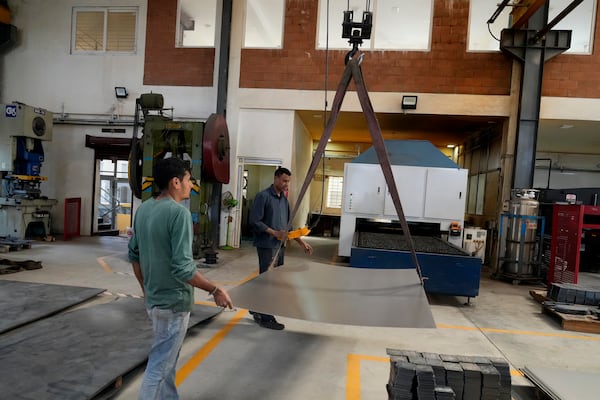 Workers move a large steel sheet to place in a laser cutting machine at a factory in a suburb of Bengaluru, India, Thursday, Feb. 27, 2025. (AP Photo/Aijaz Rahi)