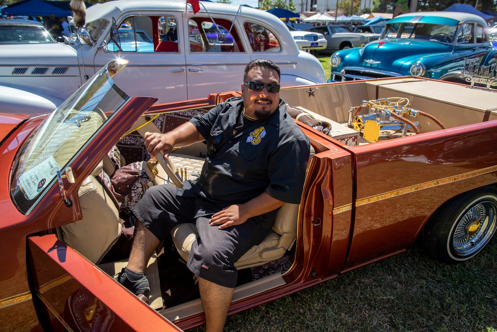 Kenneth Santillan, of San Antonio, Texas sits at the steering wheel of a 1993 Nissan Hardbody at a lowrider exhibition during the 20th anniversary of Lincoln Park in El Paso, Texas, Sunday, Sept. 22, 2024. (AP Photo/Andrés Leighton)