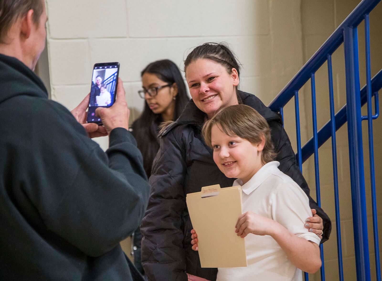 Jason Highsmith (left) takes a photo of his son, Harper-Archer Elementary 4th grader Gavin Highsmith (right) and his wife, Jessica Fullington (center), after Gavin received an award for most improved in math during the school's first awards ceremony, Friday, January 24, 2020. (ALYSSA POINTER/ALYSSA.POINTER@AJC.COM)