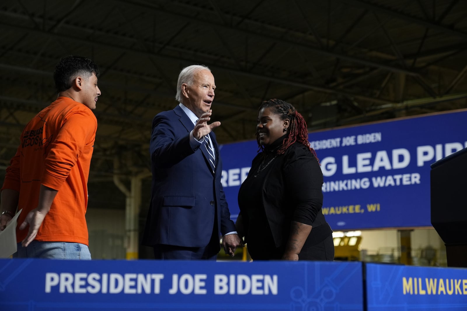 President Joe Biden, standing with Alonso Romo, LiUNA Local 113 & introducer, left, and Shy McElroy, advocate & introducer, right, waves to the audience after speaking at an event at the Milwaukee Department of Public Works in Milwaukee, Tuesday, Oct. 8, 2024, to discuss his administration's progress in replacing lead pipes in Wisconsin and across the country. (AP Photo/Susan Walsh)