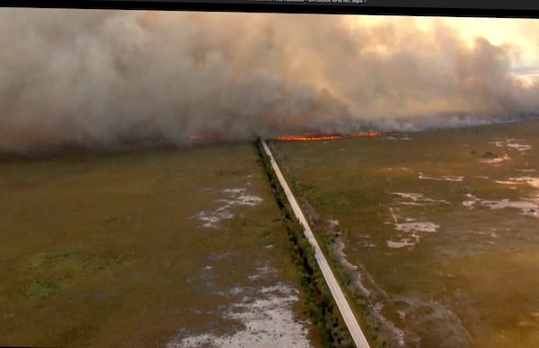 In this In this image taken from video provided by WSVN-TV,, brush fire burns across and over Card Sound Road, the only other road connecting the Keys to Florida City on the mainland, as it remains closed Tuesday, March 18, 2025, south of Dade County, Fla. (WSVN-TV via AP)