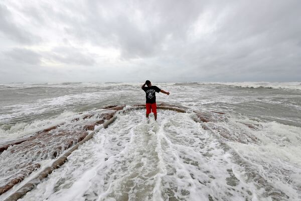 Luis Perez watches waves crash again a jetty in Galveston, Texas as Hurricane Harvey intensifies in the Gulf of Mexico Friday, Aug. 25, 2017. Harvey is forecast to be a major hurricane when it makes landfall along the middle Texas coastline. (AP Photo/David J. Phillip)