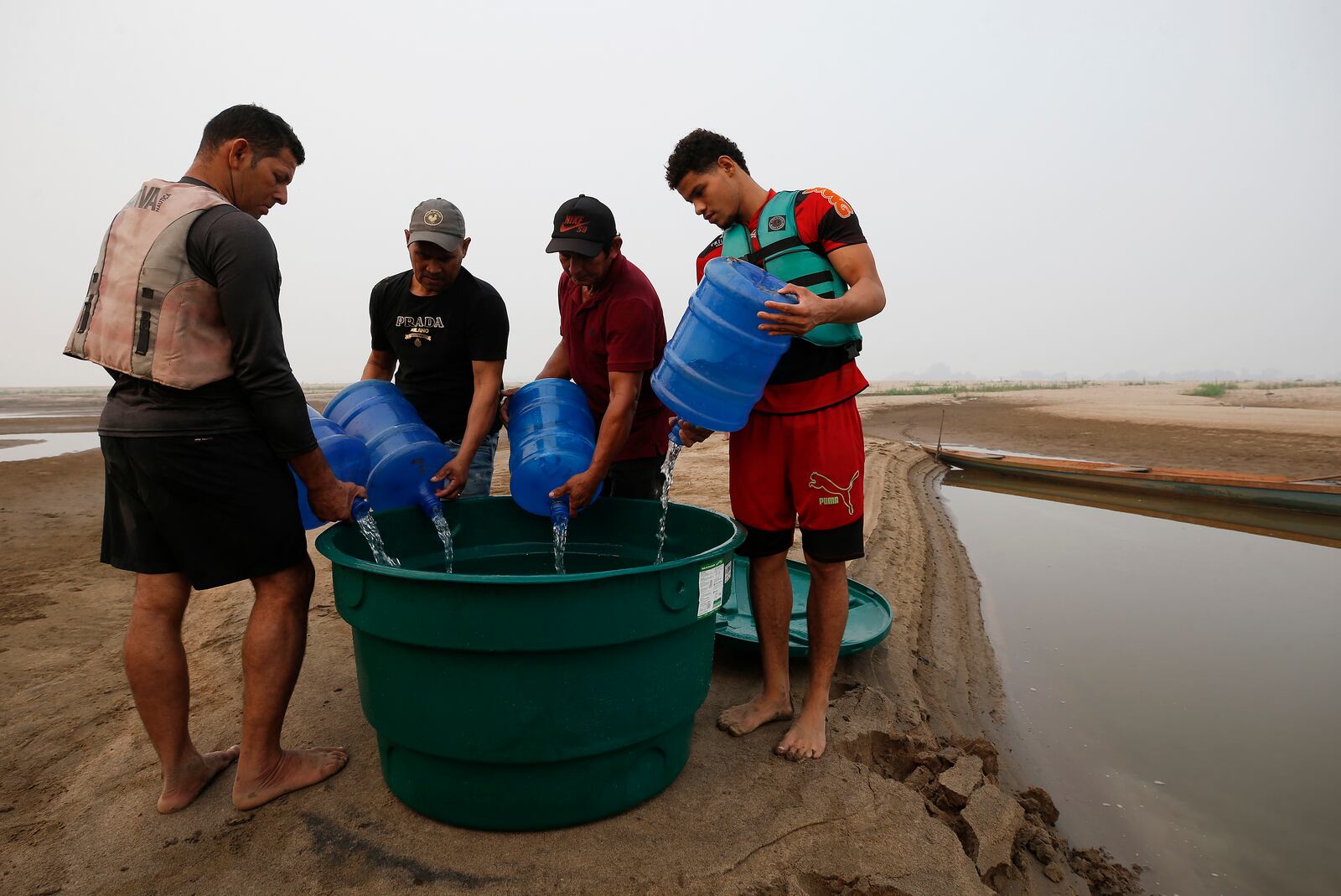 Residents fill a container with drinking water at the Madeira River, a tributary of the Amazon River, during dry season in Humaita, Amazonas state, Brazil, Sunday, Sept. 8, 2024. (AP Photo/Edmar Barros)