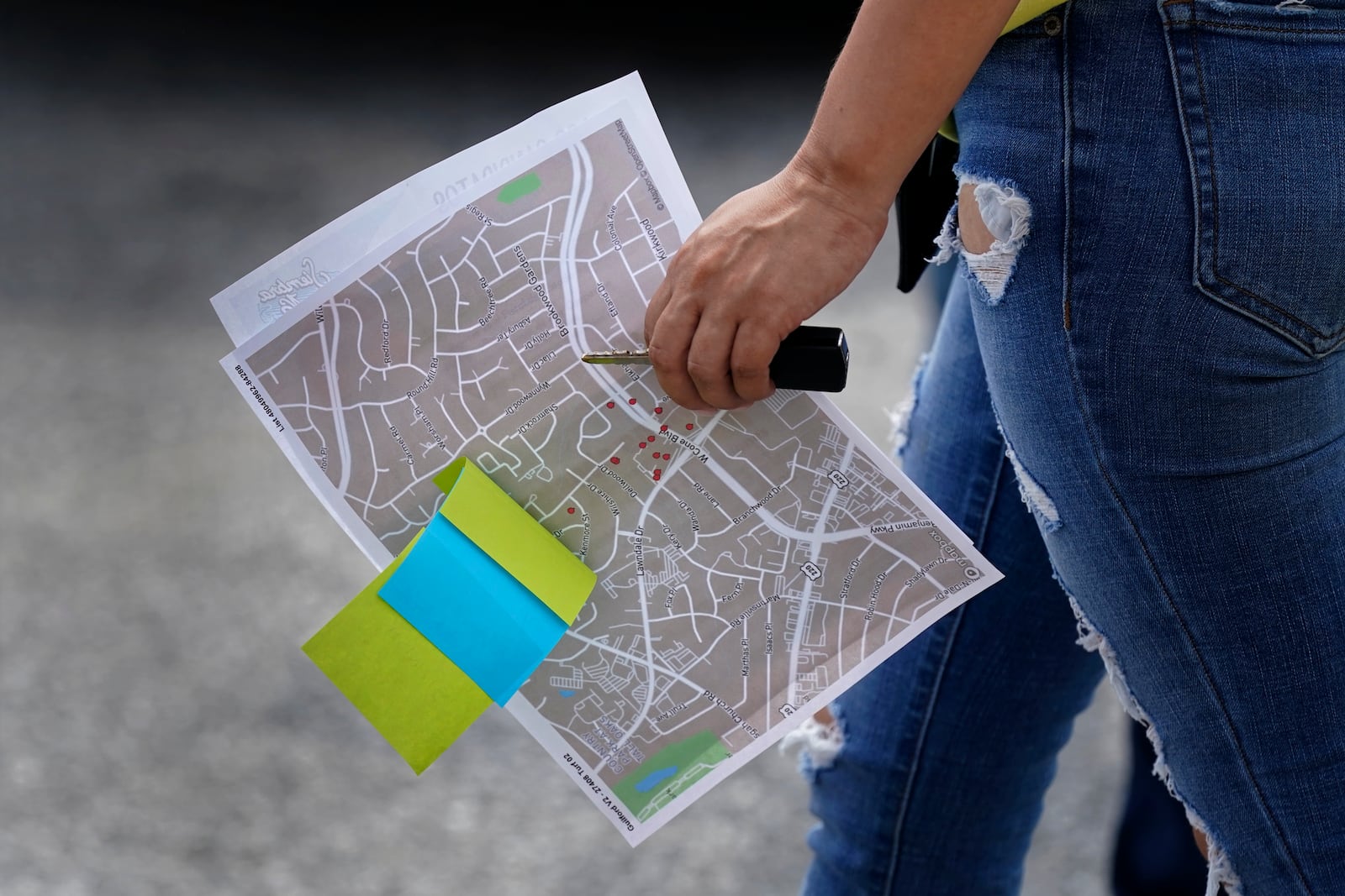 A woman carries a map to homes she and her partner will visit during a voter engagement event for the Latino community in Greensboro, N.C., Saturday, Sept. 21, 2024. (AP Photo/Chuck Burton)