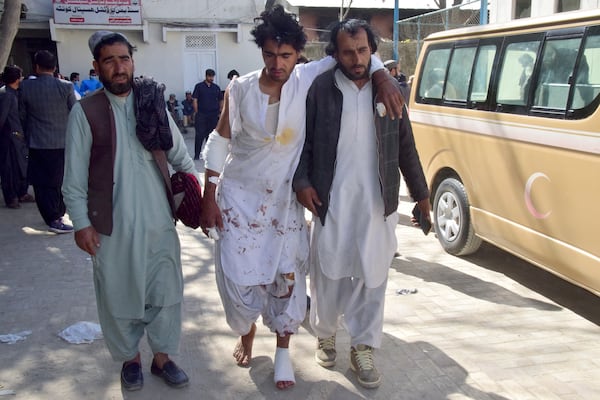 A man, who was injured in a bomb explosion at railway station, walks with help of his relatives after receiving initial treatment at a hospital, in Quetta, southwestern Pakistan, Saturday, Nov. 9, 2024. (AP Photo/Arshad Butt)