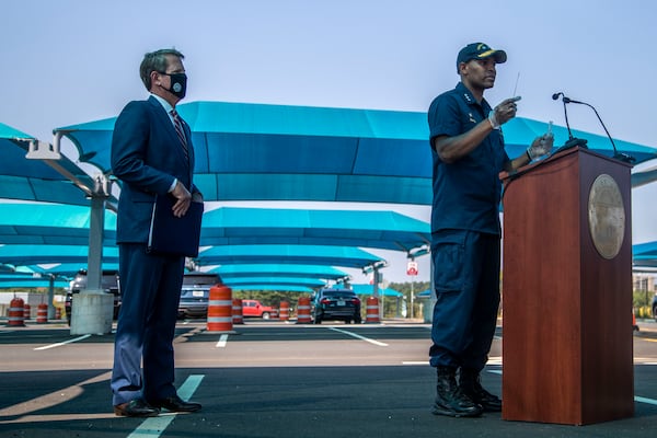 Gov. Brian Kemp (left) watches as U.S. Surgeon General Vice Admiral Jerome M. Adams prepares to self-administer a COVID-19 test during a press conference at a drive-thru COVID-19 testing clinic located in a Hartsfield-Jackson International Atlanta Airport paid parking facility in College Park, Monday, August 10, 2020. (ALYSSA POINTER / ALYSSA.POINTER@AJC.COM)