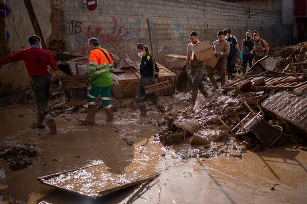 Members of the army and police walk through streets still awash with mud while clearing debris and cleaning up after the floods in Masanasa, Valencia, Spain, Thursday, Nov. 7, 2024. (AP Photo/Emilio Morenatti)