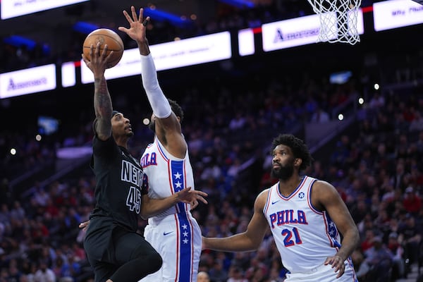 Brooklyn Nets' Keon Johnson, left, goes up for a shot against Philadelphia 76ers' Paul George, center, and Joel Embiid during the first half of an NBA basketball game, Saturday, Feb. 22, 2025, in Philadelphia. (AP Photo/Matt Slocum)