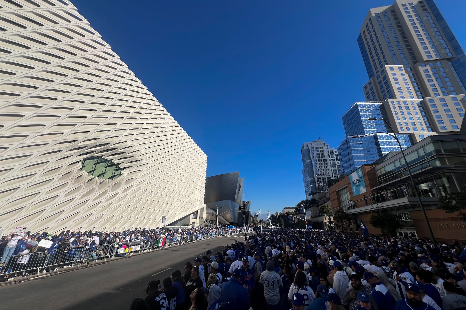 Fans crowd the sidewalk as they wait for the start of the Los Angeles Dodgers baseball World Series championship parade Friday, Nov. 1, 2024, in Los Angeles. (AP Photo/Kyusung Gong)