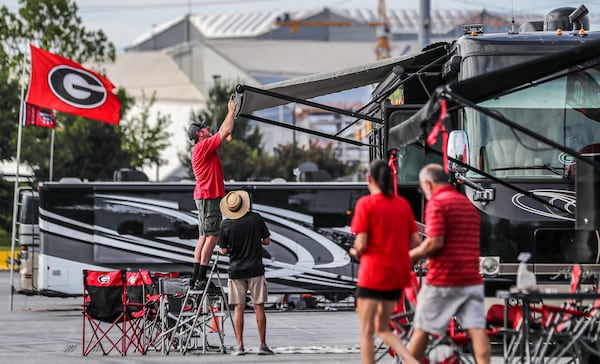 September 2, 2022 Atlanta: Left to right - UGA RV enthusiasts, Brent Lovern from Bogart, Georgia tries to fix the awning of Lindsay Greeson from Winder, Georgia as Melanie and Barton Carty from outside of Monroe, Georgia come around the corner to help at the Marshalling Yard at the Georgia World Congress Center where college football RV enthusiasts are parked. in the shadow of Mercedes-Benz Stadium. College football fans began filtering into downtown Atlanta on Friday, Sept. 2, 2022 for SaturdayÕs big game with the defending College Football National Champions, the Georgia Bulldogs set to take on the #11 Oregon Ducks in the Chick-fil-A kickoff game at Mercedes-Benz Stadium. (John Spink / John.Spink@ajc.com)

