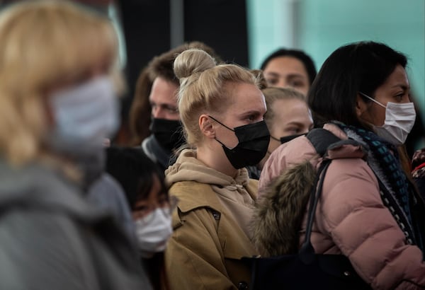 Passengers wearing masks line up as they wait to check in at Barcelona airport, Spain, Saturday, March 14, 2020. Spain's prime minister has announced a two-week state of emergency from Saturday in a bid to contain the new coronavirus outbreak. For most people, the new coronavirus causes only mild or moderate symptoms. For some, it can cause more severe illness, especially in older adults and people with existing health problems. (AP Photo/Emilio Morenatti)