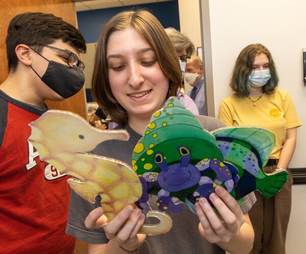 Lakeside High School Art Club member Lili Toll (center) looks over the sea creature she made to hang on a blue wall of a pediatric exam room at the Atlanta Urgent Care nearby. PHIL SKINNER FOR THE ATLANTA JOURNAL-CONSTITUTION