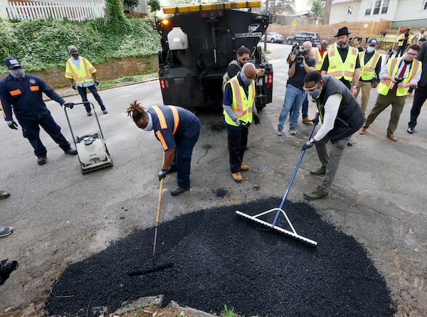 After some instructions, Mayor Andre Dickens (right) tries his hand at repairing a pothole.  Dickens and ATLDOT Commissioner Josh Rowan joined the "pothole posse" ahead of Mayor Dickens' 100th day in office In Atlanta on Monday, April 11, 2022.  Mayor Dickens announced at his April 4 State of the City that he was bringing back the pothole posse, a program started by former mayor Shirley Franklin in the early 2000s.(Bob Andres / robert.andres@ajc.com)