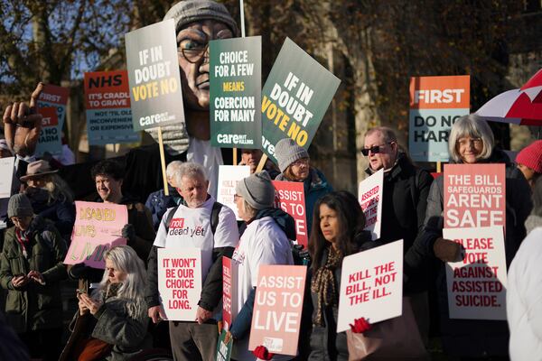 Protesters show placards in front of Parliament in London, Friday, Nov. 29, 2024 as British lawmakers started a historic debate on a proposed to help terminally ill adults end their lives in England and Wales.(AP Photo/Alberto Pezzali)