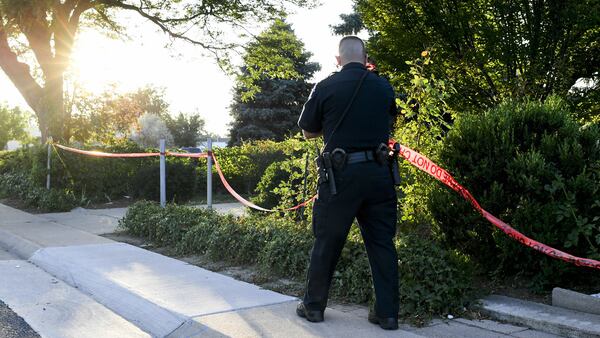 In this July 30, 2018, photo, an Aurora police officer removes crime scene tape from the outside of a home where homeowner Richard "Gary" Black Jr., 73,  was shot and killed by police that morning. Black, a Vietnam veteran, was killed moments after killing an intruder who broke into his home and attacked his 11-year-old grandson. The officer who killed Black has been cleared of criminal wrongdoing.