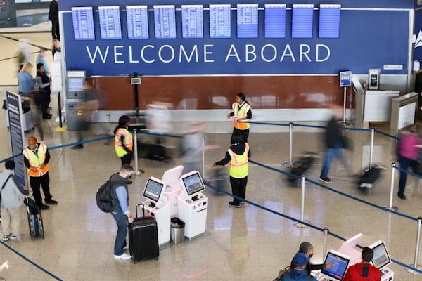 As airport agents assist passengers at Hartsfield-Jackson Atlanta International Airport, people walk towards a ticketing line. This coming holiday season, Airport crowds are expected as Thanksgiving travel rebounds. Miguel Martinez / miguel.martinezjimenez@ajc.com