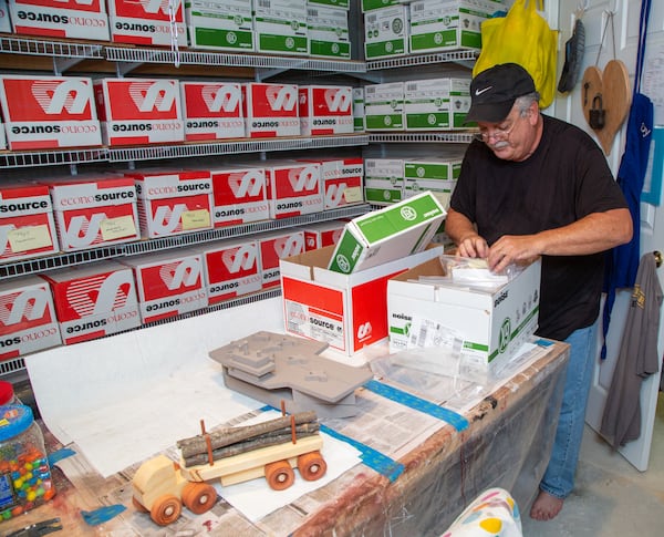 Jon Saulson sorts through boxes of his woodcraft creations in the basement of his Snellville home. PHIL SKINNER FOR THE ATLANTA JOURNAL-CONSTITUTION.