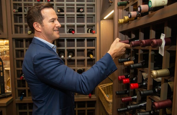 Ryan Cone gets a bottle of wine from the wine cellar of his Brookhaven home.PHIL SKINNER FOR THE ATLANTA JOURNAL-CONSTITUTION.