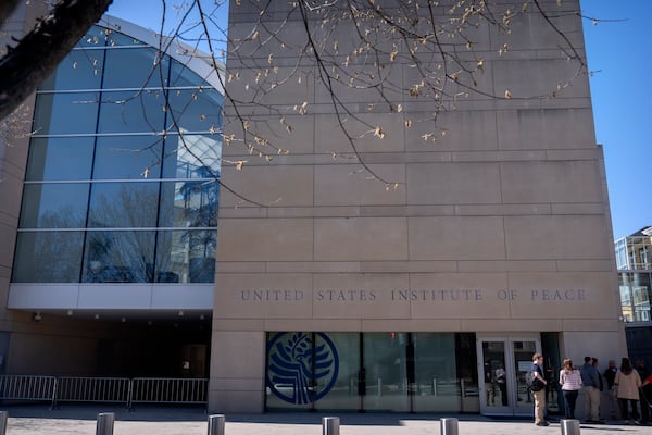 People stand outside the headquarters of the United States Institute of Peace, Tuesday, March 18, 2025, in Washington. (AP Photo/Mark Schiefelbein).