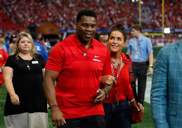 090322 Atlanta, Ga.: Former Georgia football player and Republican U.S. Senate candidate Herschel Walker walks with his wife, Julie, as they leave the field before Georgia’s game against the Oregon Ducks at Mercedes Benz Stadium, Saturday, September 3, 2022, in Atlanta. The Walker’s were on the field to honor former Georgia football coach Vince Dooley. (Jason Getz / Jason.Getz@ajc.com)