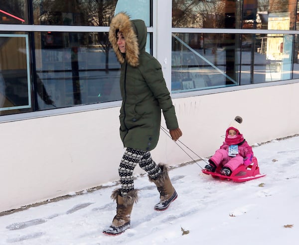   Katye Watts gives her daughter Finley, almost 3, a lift down North Highland Avenue on her way to a coffee shop.     BOB ANDRES  /BANDRES@AJC.COM