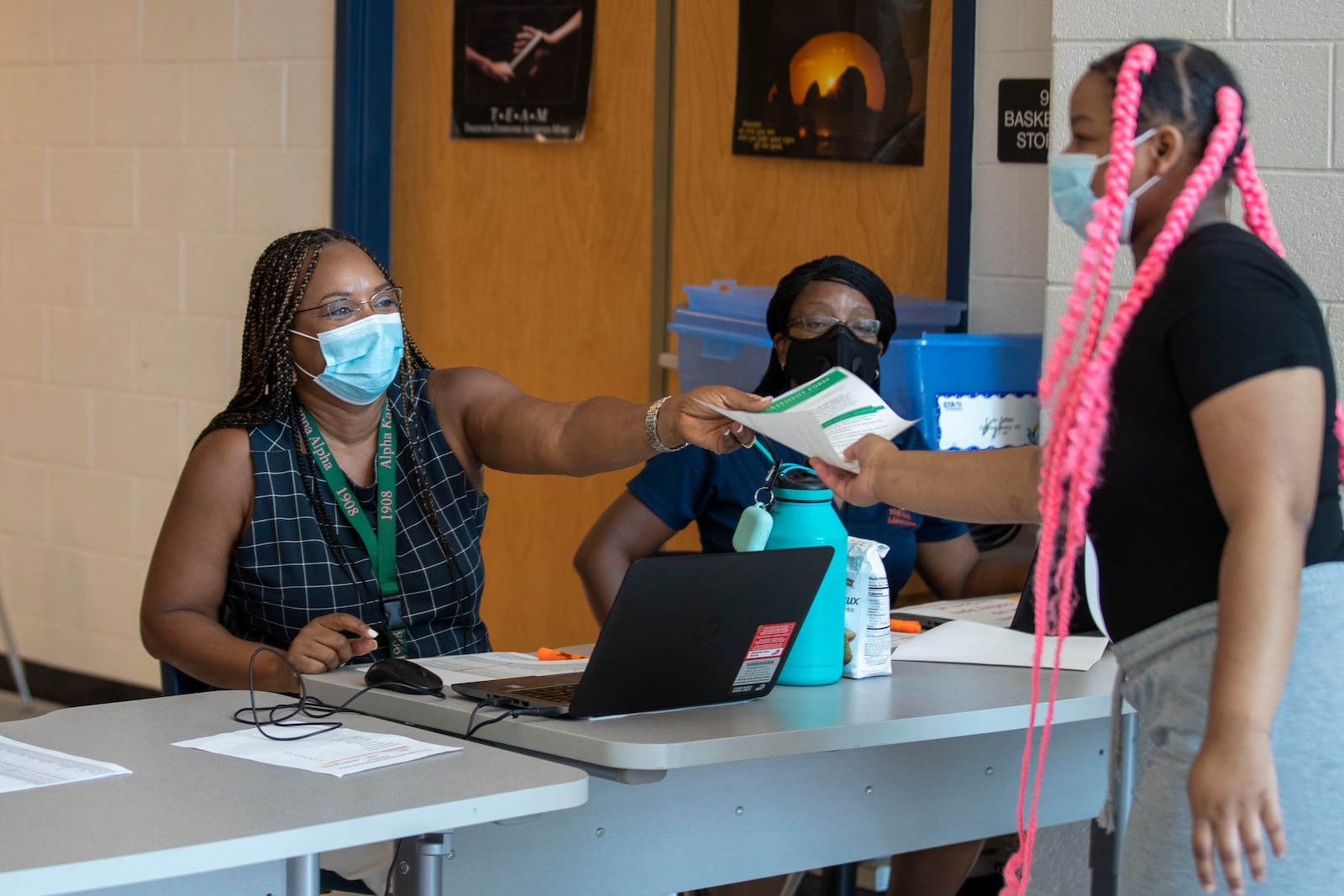 Mundy's Mill High School assistant principal Sharon Wilson hands a student a paperwork for a laptop during a laptop distribution at the school in Jonesboro, Georgia, on Sept. 1, 2020. (Alyssa Pointer / Alyssa.Pointer@ajc.com)