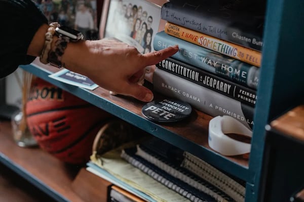 Momentos from Pete Buttigieg’s 2020 presidential run are displayed on a shelf in Emily Voorde’s home on February 7, 2024, in South Bend, Indiana. Voorde served as Pete Buttigieg’s husband Chasten Buttigieg’s full-time body woman on the campaign trail. Voorde also inspired Secretary of Transportation Buttigieg’s comprehensive disability policy. (Photo Courtesy of Jamie Kelter Davis, The 19th)