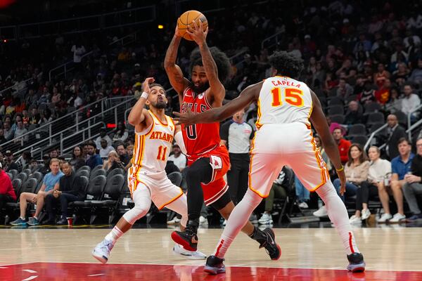 Chicago Bulls guard Coby White (0) goes between Atlanta Hawks guard Trae Young (11) and center Clint Capela (15) during the first half of an NBA basketball game Saturday, Nov. 9, 2024, in Atlanta. (AP Photo/ John Bazemore)