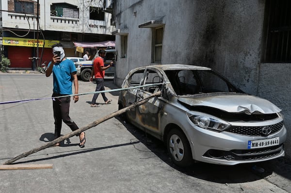 Passerby take photos of a burnt vehicle a day after communal clashes sparked by protests demanding removal of the tomb of 17th-century Muslim Mughal ruler Aurangzeb in Nagpur, India, Tuesday, March 18, 2025. (AP Photo)