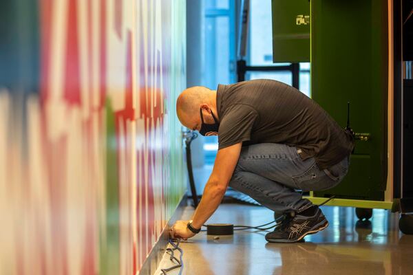 A worker sets up electrical wires as State Farm Arena prepares to host Fulton County early voting in Atlanta, Friday, July 17, 2020. State Farm Arena, home of the Atlanta Hawks, will host early voting and the 2020 presidential election for Fulton County registered voters.  (ALYSSA POINTER / ALYSSA.POINTER@AJC.COM)