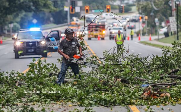 Crews working for several hours Thursday, Aug. 31, 2023, to remove a fallen tree that blocked Roswell Road in Sandy Springs. The Atlanta area recorded another half-inch of rainfall Wednesday as Hurricane Idalia passed to the south. (John Spink / John.Spink@ajc.com)