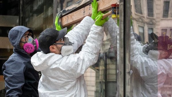 Carpenters wear protective gear as they board up the closed Sephora store on 34th St., Friday, March 20, 2020, in New York. New York Gov. Andrew Cuomo is ordering all workers in non-essential businesses to stay home and banning gatherings statewide. "Only essential businesses can have workers commuting to the job or on the job," Cuomo said of an executive order he will sign Friday. (AP Photo/Mary Altaffer)