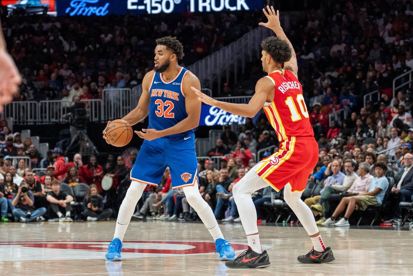 New York Knicks center Karl-Anthony Towns (32) attempts to pass the ball while guarded by Atlanta Hawks forward Zaccharie Risacher (10) during the second half of an NBA basketball game, Wednesday, Nov. 6, 2024, in Atlanta. (AP Photo/Jason Allen)