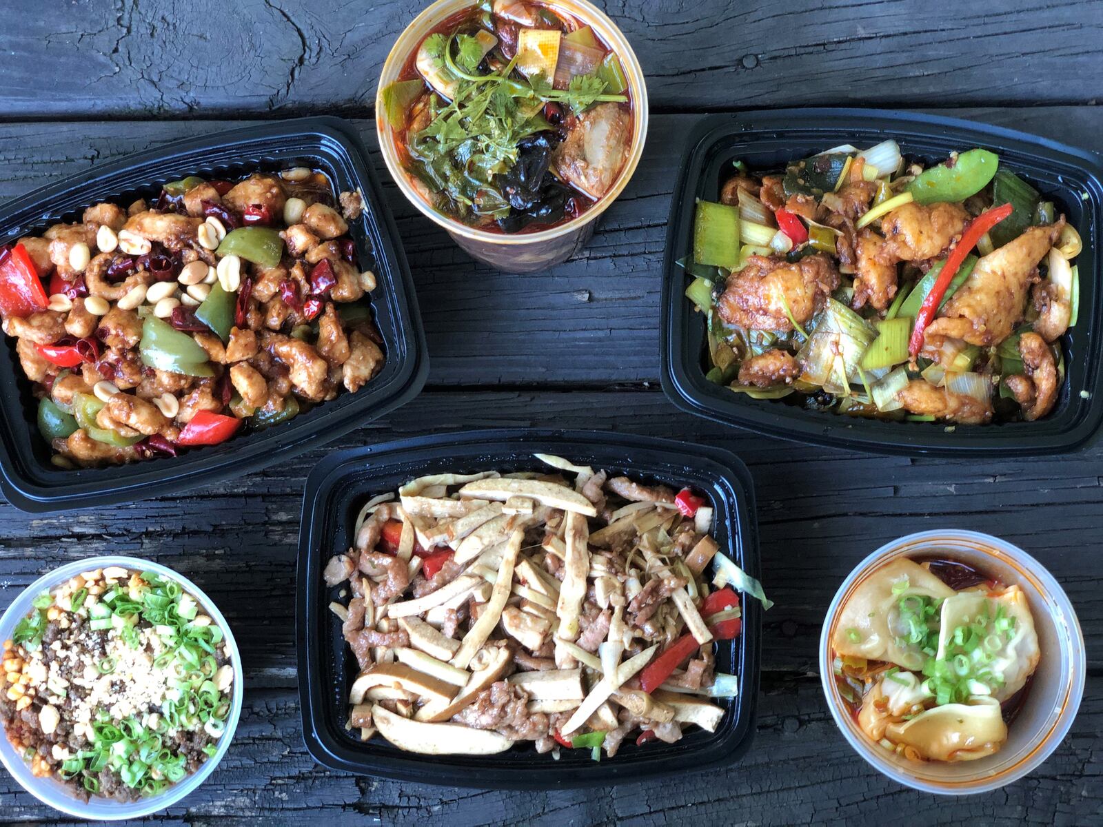 A takeout order from Fire Stone Chinese Cuisine includes (clockwise from upper left) kung pao chicken, duck in stone pot, Hunan stir-fry with fish, red chili oil wontons, smoked tofu with shredded pork and bamboo shoots, and dan dan noodles. CONTRIBUTED BY WENDELL BROCK