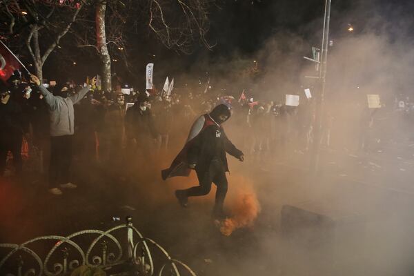 A protester kicks a flare against riot policemen during a protest after Istanbul's Mayor Ekrem Imamoglu was arrested and sent to prison, in Istanbul, Turkey, Sunday, March 23, 2025. (AP Photo/Huseyin Aldemir)