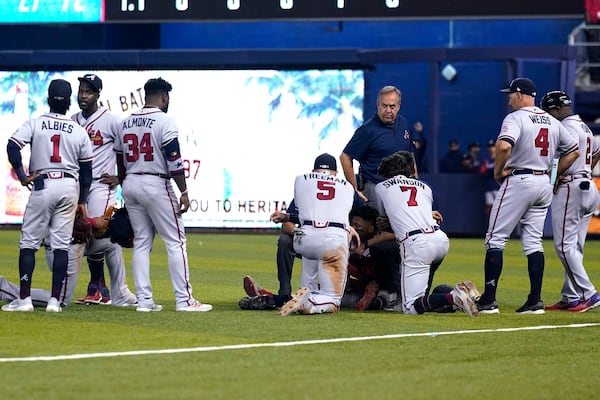 Braves teammates gather around right fielder Ronald Acuna, lying on his back, after he attempted to walk after injuring his knee during the fifth inning Saturday, July 10, 2021, in Miami. (Lynne Sladky/AP)