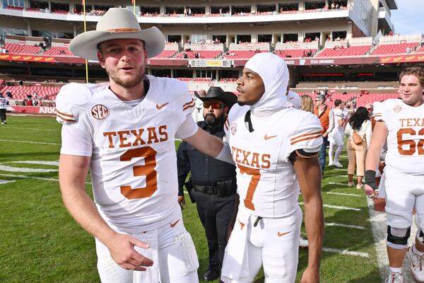 Texas quarterback Quinn Ewers (3) celebrates with teammate Isaiah Bond (7) after defeating Arkansas 20-10 in an NCAA college football game Saturday, Nov. 16, 2024, in Fayetteville, Ark. (AP Photo/Michael Woods)