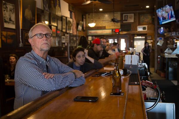 Bill Fallin (left) watches Donald J. Trump’s inauguration on one of the many televisions at Manuel’s Tavern on Friday in Atlanta. STEVE SCHAEFER / SPECIAL TO THE AJC