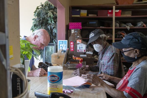 Joe Jordan (center) and Hattie Jordan (right), owners of Cato Shoe Repair, complete a transaction for customer Mike Marshall (left) as he picks up a pair of shoes at the store in Atlanta. Marshall says he’s been a customer at Cato Shoe Repair for 20 years. (ALYSSA POINTER / ALYSSA.POINTER@AJC.COM)