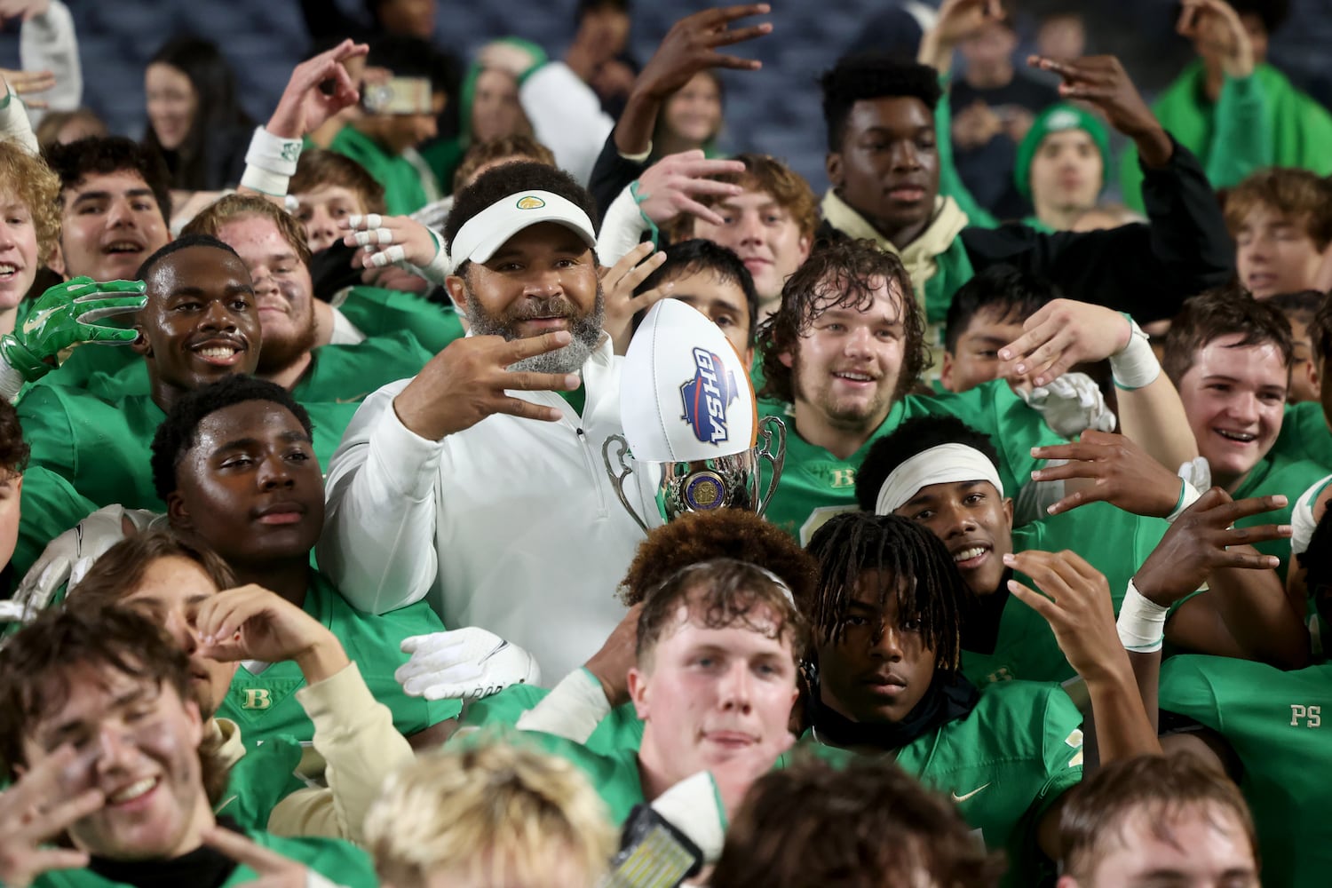 Buford head coach Bryant Appling, center, and players hold up three fingers after their third state championship in a row after their 21-20 win against Langston Hughes in the Class 6A state title football game at Georgia State Center Parc Stadium Friday, December 10, 2021, Atlanta. JASON GETZ FOR THE ATLANTA JOURNAL-CONSTITUTION